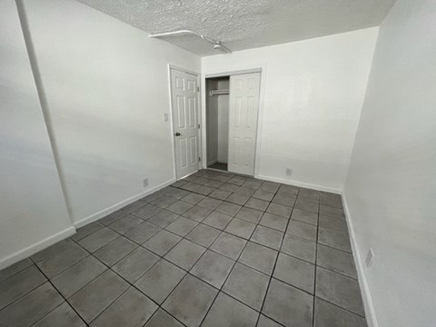 A room with white walls and tile flooring with two doors.
