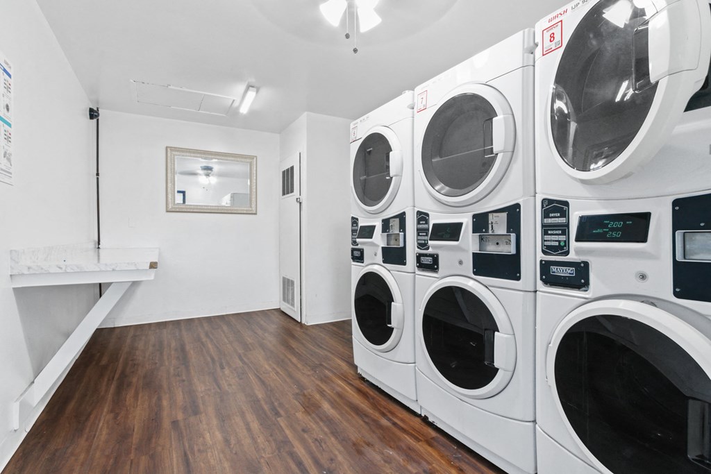a washer and dryer in a laundry room with wood floors and white walls