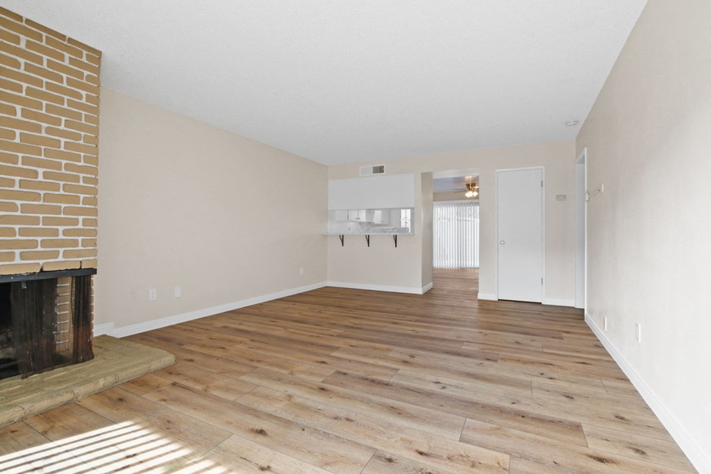 an empty living room with wood flooring and a fireplace