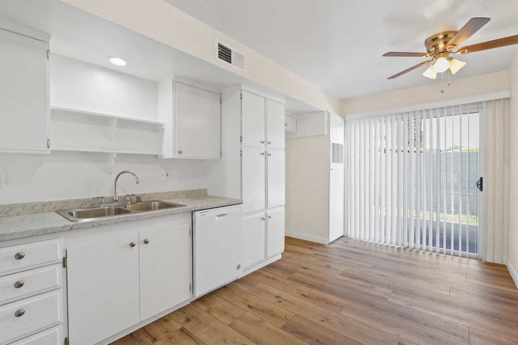 an empty kitchen with white cabinets and a ceiling fan