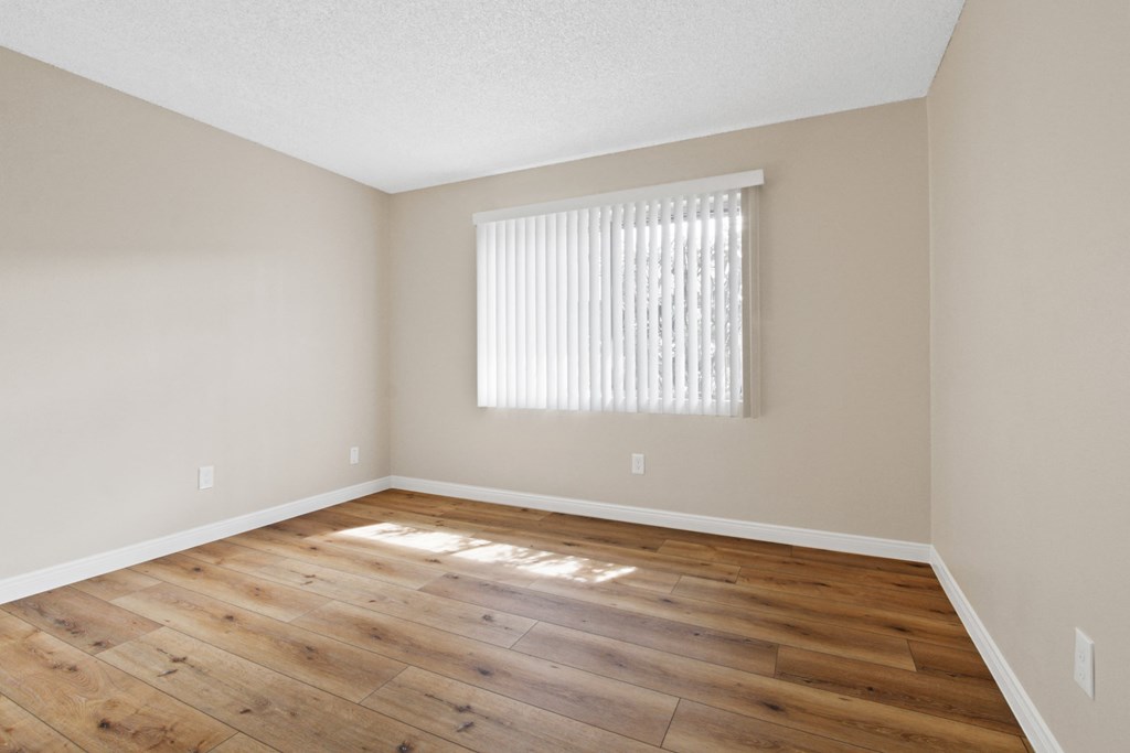 an empty living room with wood floors and a window