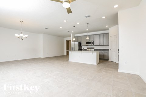 a large kitchen and living room with white tile flooring and white cabinets