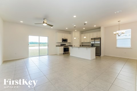 an open kitchen and living room with white tile flooring and a large white island