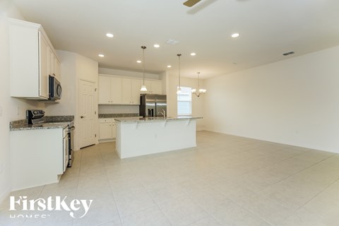 an open kitchen and living room with white cabinets and tile flooring