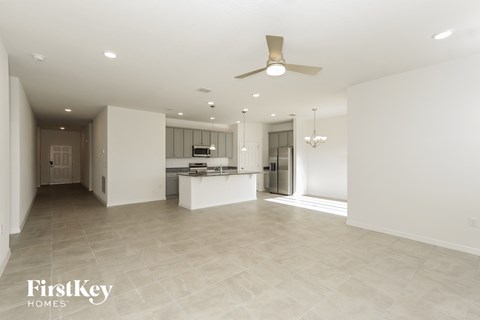 A spacious, empty room with a fan and a chandelier.
