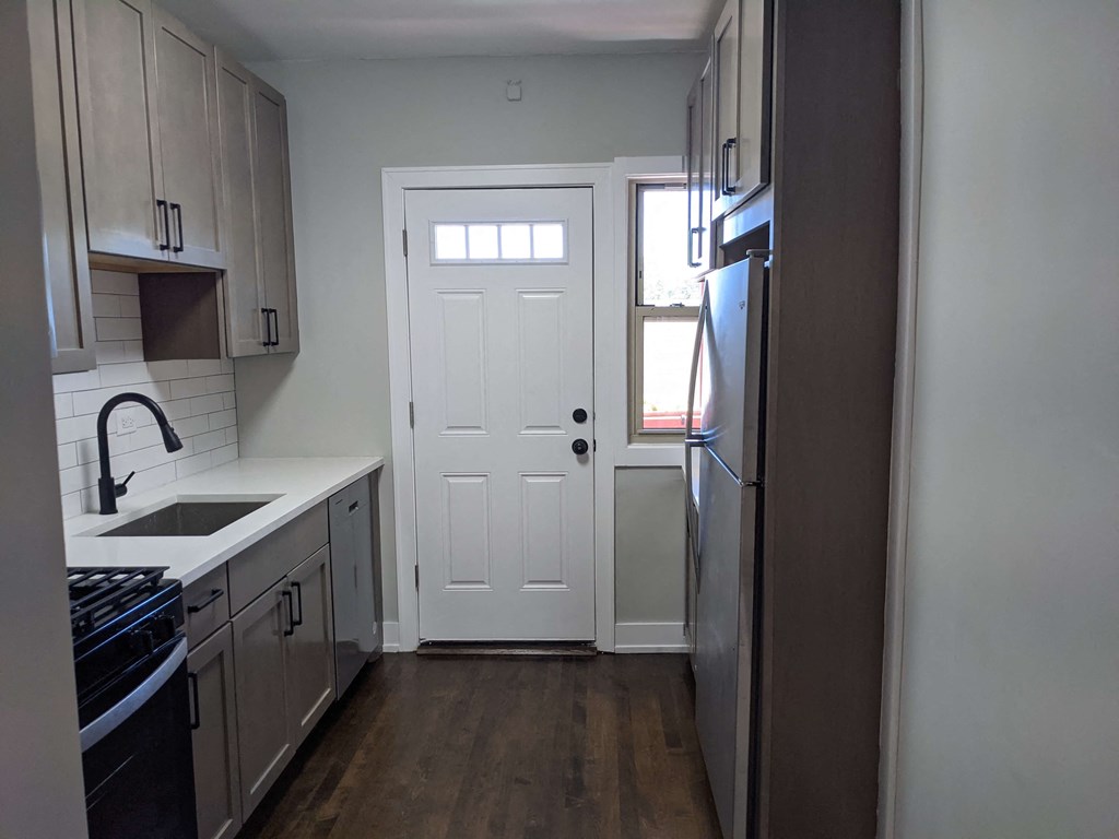 an empty kitchen with a white door and a window