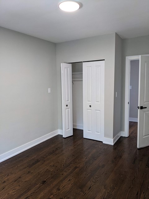 an empty living room with wood floors and white doors