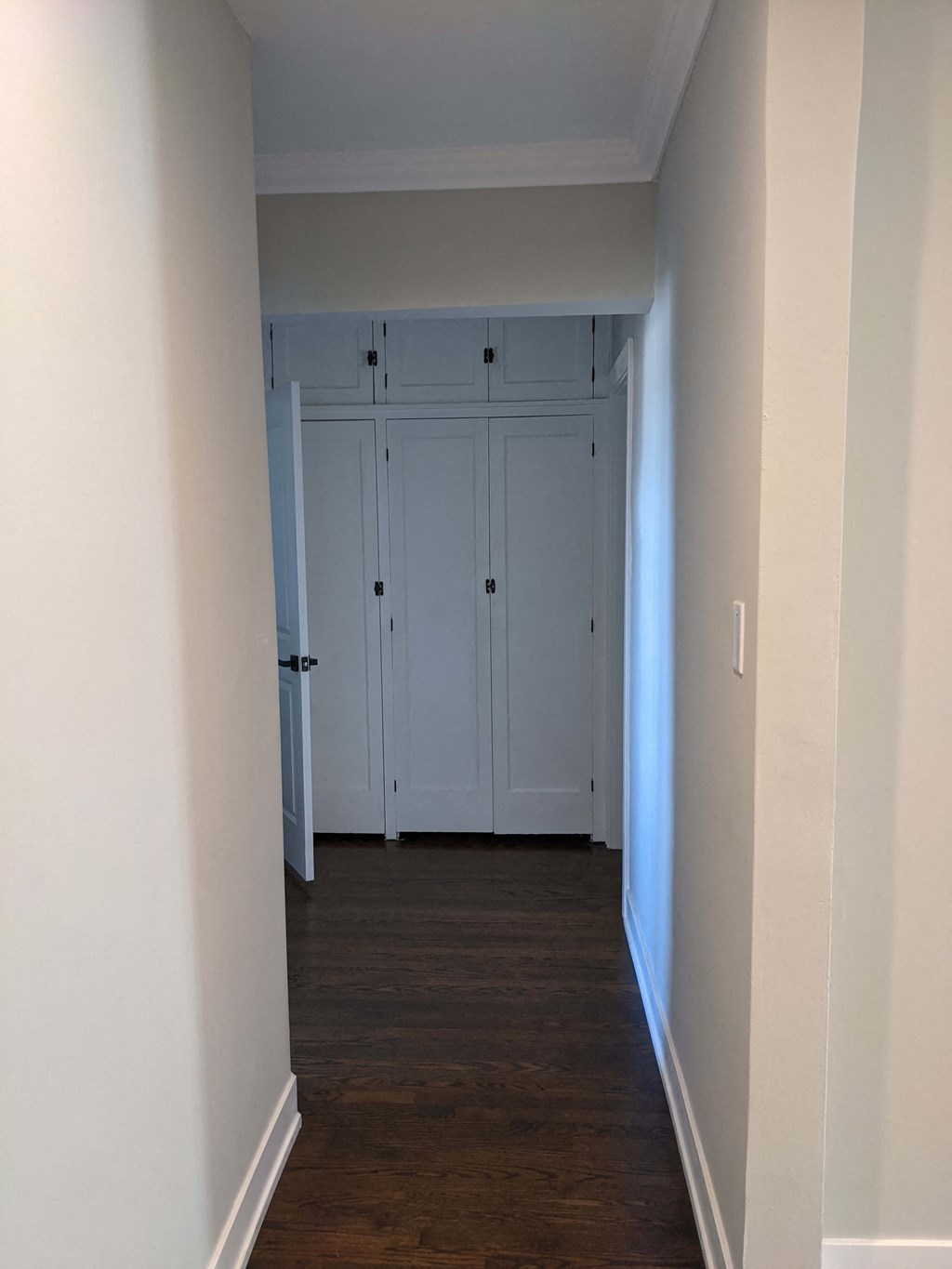 a hallway with wood floors and white closets with doors