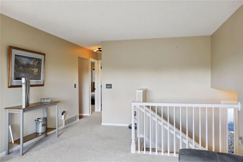 a living room with a staircase and a painting on the wall