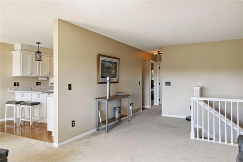 an empty living room with a staircase and a kitchen