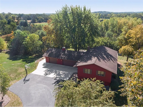 an aerial view of a red house with a roof and a driveway