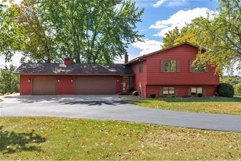 a red house with a driveway and a tree