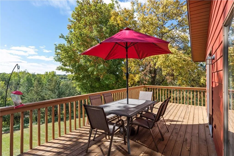 a table with a red umbrella on a deck