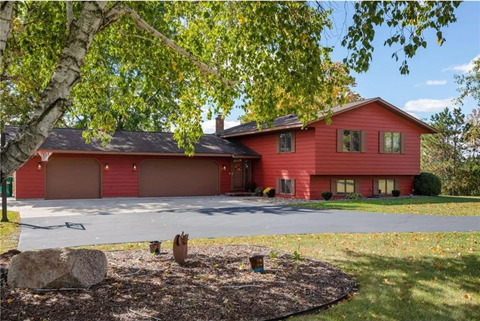 a red house with a driveway and a tree