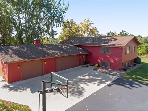 a red house with a driveway and a basketball court