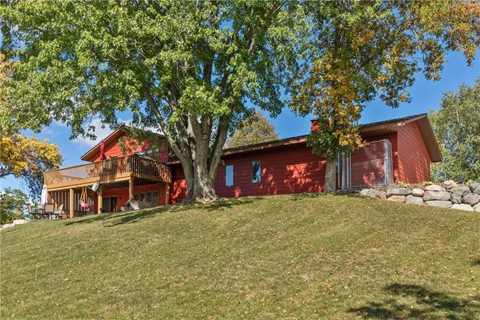 a red house on a hill with a tree in front of it