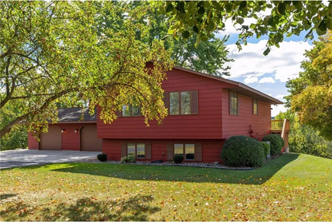 a red house with a driveway and a tree