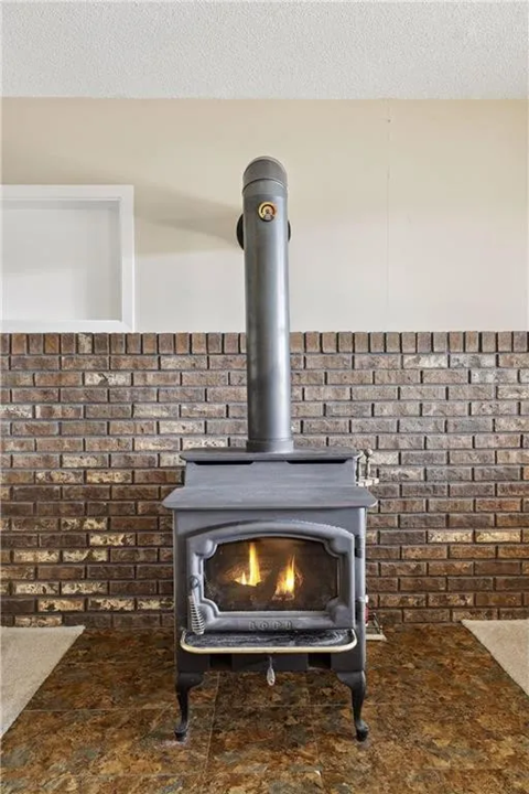 a wood stove in a living room with a brick wall