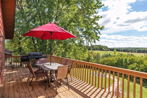 a table with a red umbrella on a deck