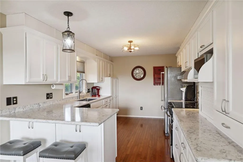 a kitchen with white cabinets and marble counter tops