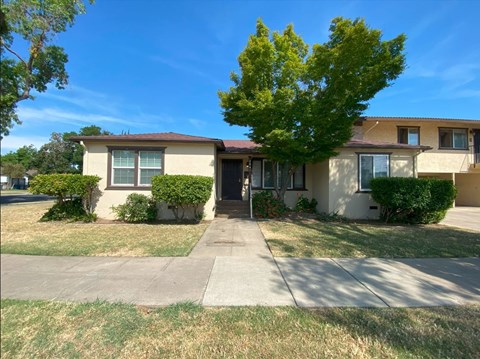 A house with a brown roof and a tree in front.