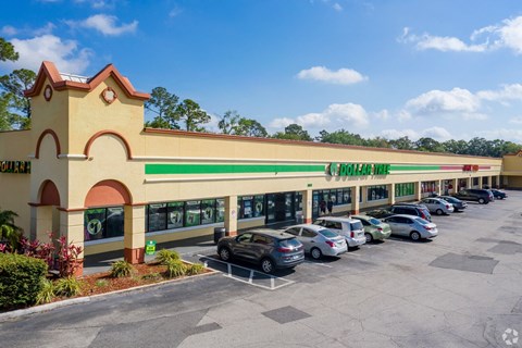 the exterior of a shopping center with cars parked in front of it
