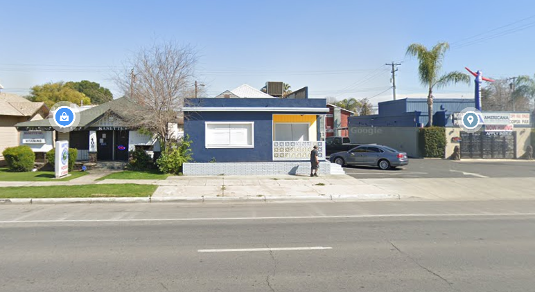 a small blue building on the corner of a street