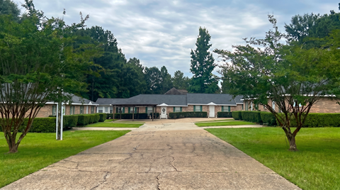 A long driveway leads to a building surrounded by trees.