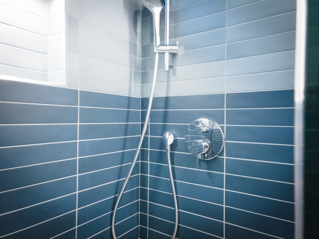 a shower in a blue tiled bathroom