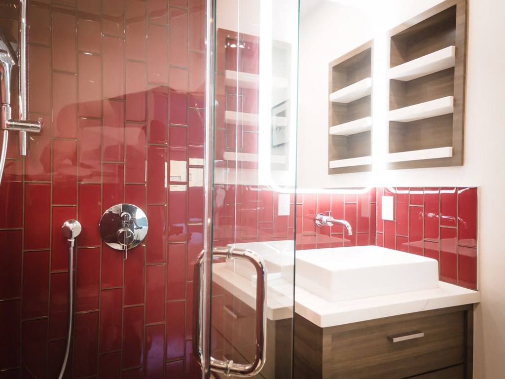 a red tiled bathroom with a shower and a sink