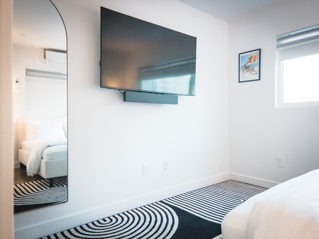 a bedroom with a tv on the wall and a large mirror