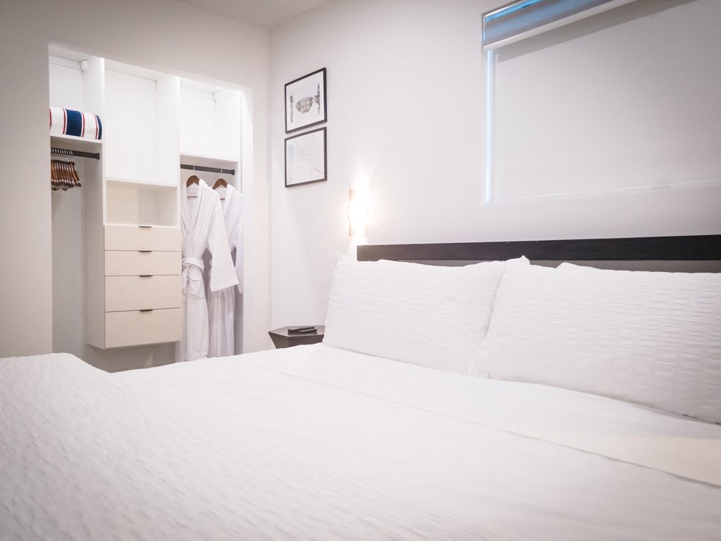 a bedroom with a white bed and a closet