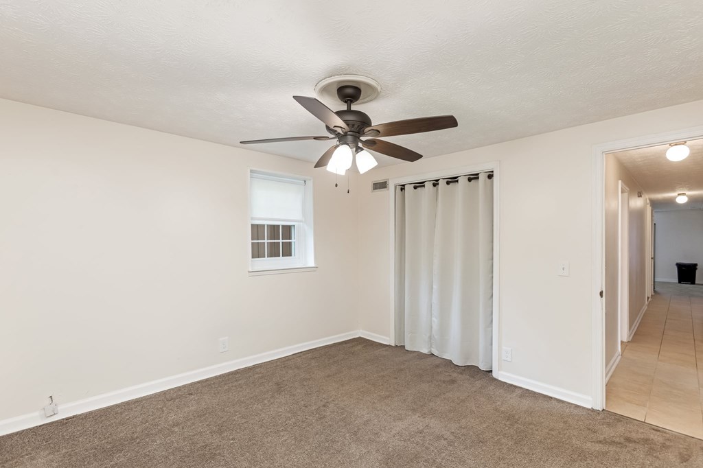 A room with a ceiling fan and carpeted floor.