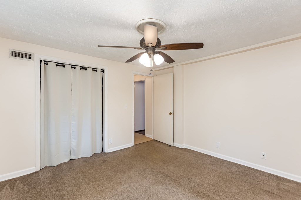 A room with a ceiling fan and carpeted floor.