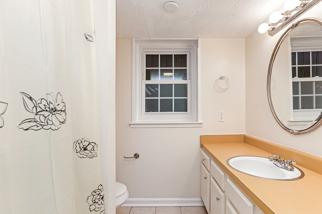 A bathroom with a sink, mirror, and shower.