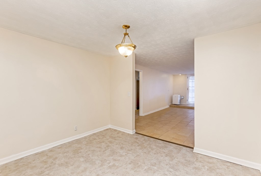 A room with a light fixture on the ceiling and a doorway leading to another room.
