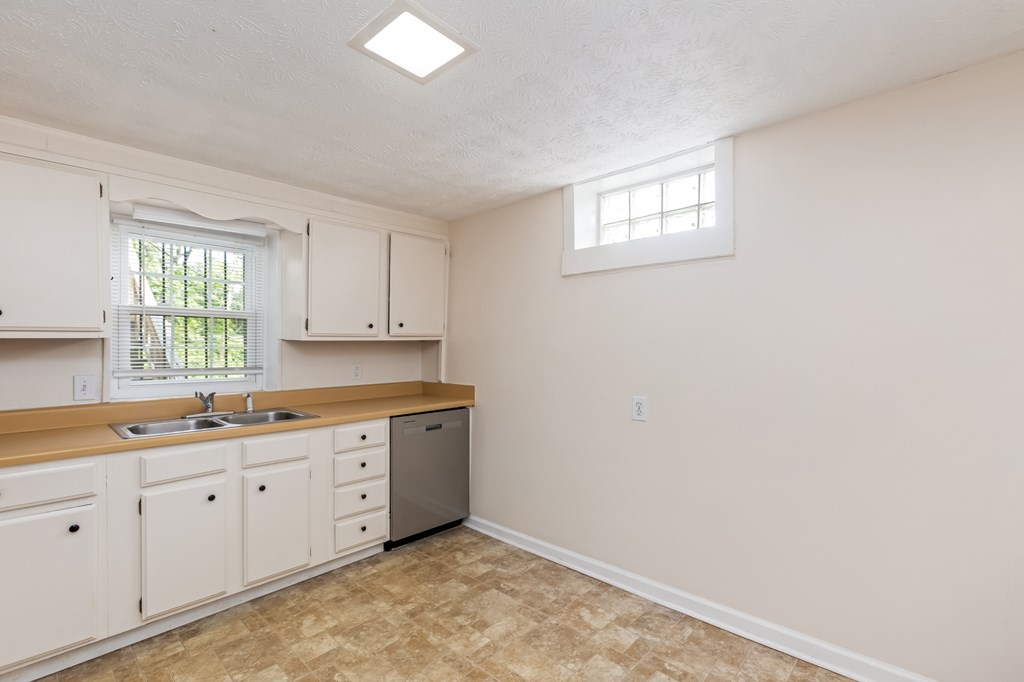 A kitchen with a sink, dishwasher, and cabinets.
