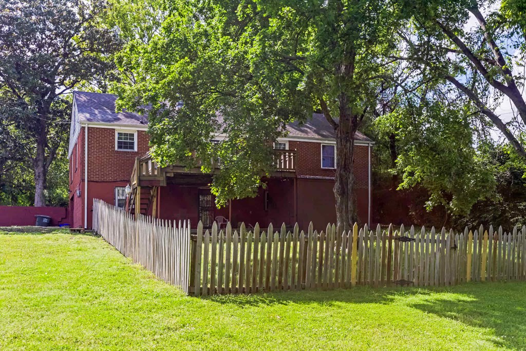 A red brick house with a white window and a wooden fence.