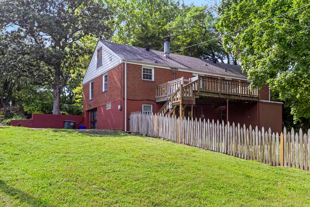 A red brick house with a white fence in front.