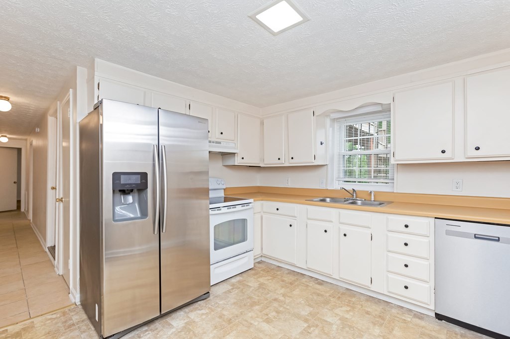 A kitchen with a stainless steel refrigerator and white cabinets.