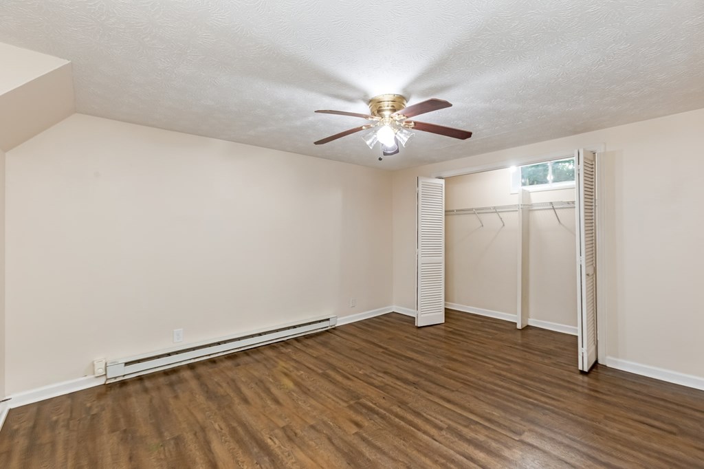 A room with a ceiling fan and wooden flooring.
