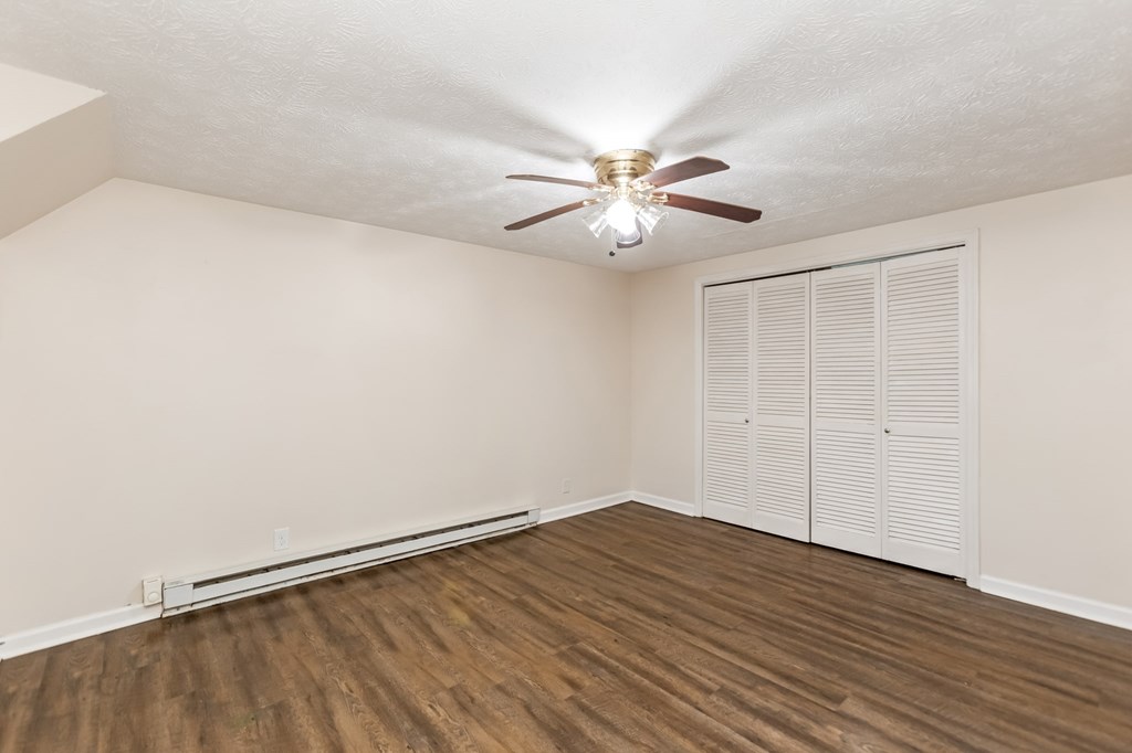 A room with a ceiling fan and wooden flooring.