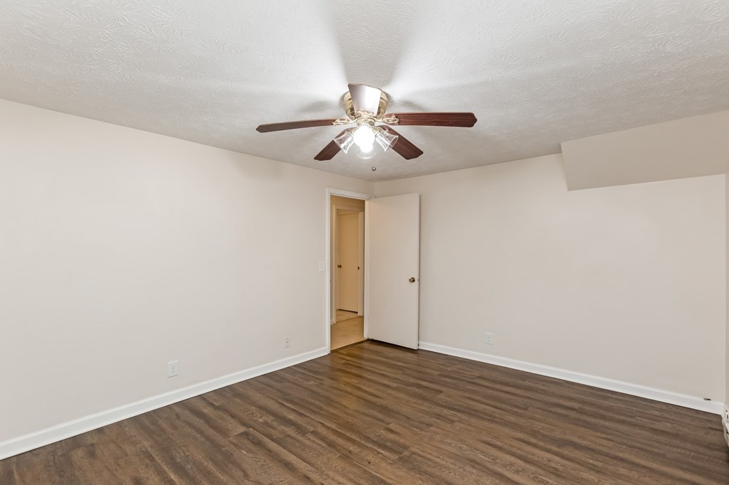 A room with a ceiling fan and wooden flooring.