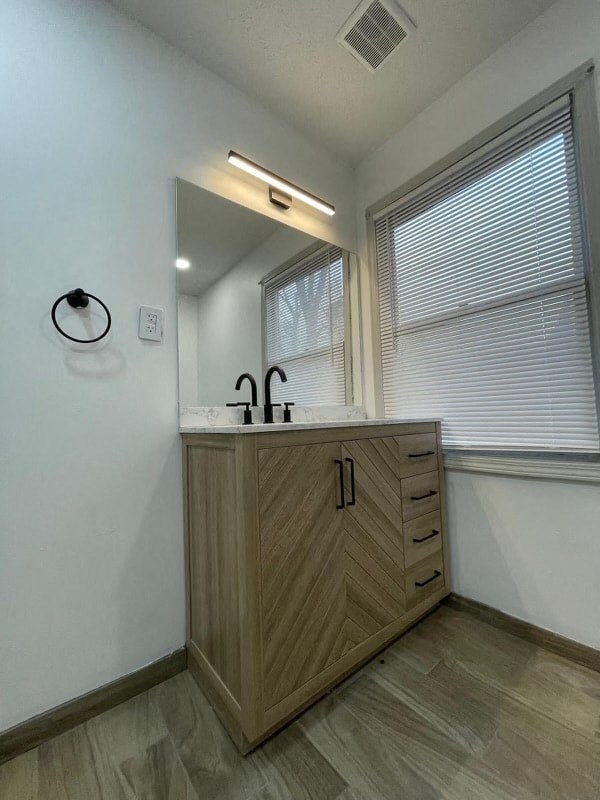 a bathroom with a sink and a mirror and a window