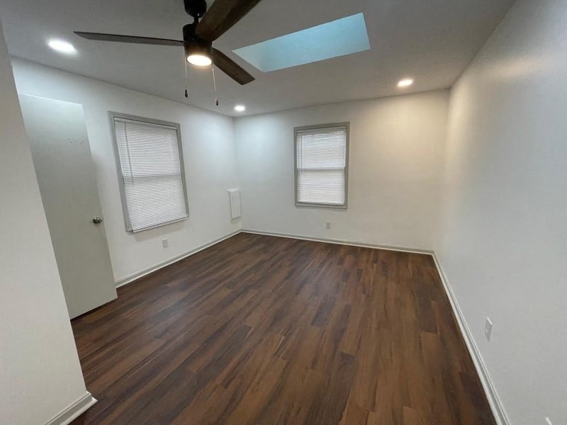an empty living room with wood floors and a ceiling fan