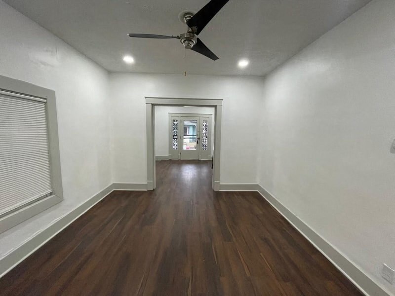 an empty living room with white walls and a ceiling fan