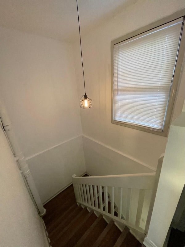 a stairway with a white railing and a window