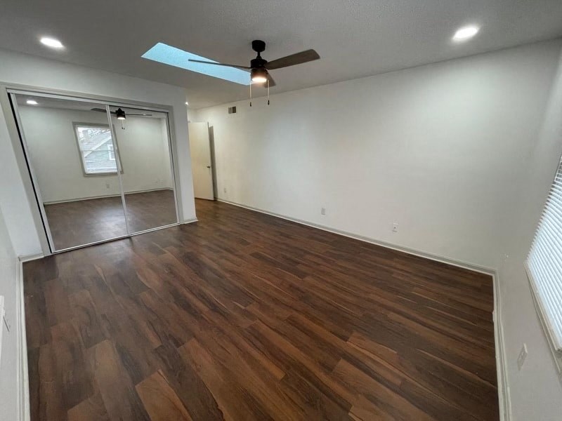 an empty living room with wood flooring and a ceiling fan