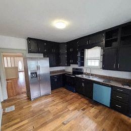 a kitchen with black cabinets and a stainless steel refrigerator