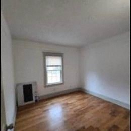 a small room with a wooden floor and a window